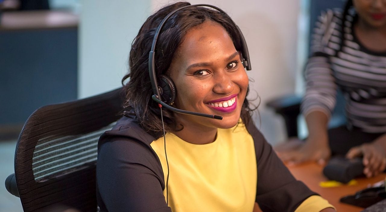 Collaboratrice souriante au téléphone avec un client