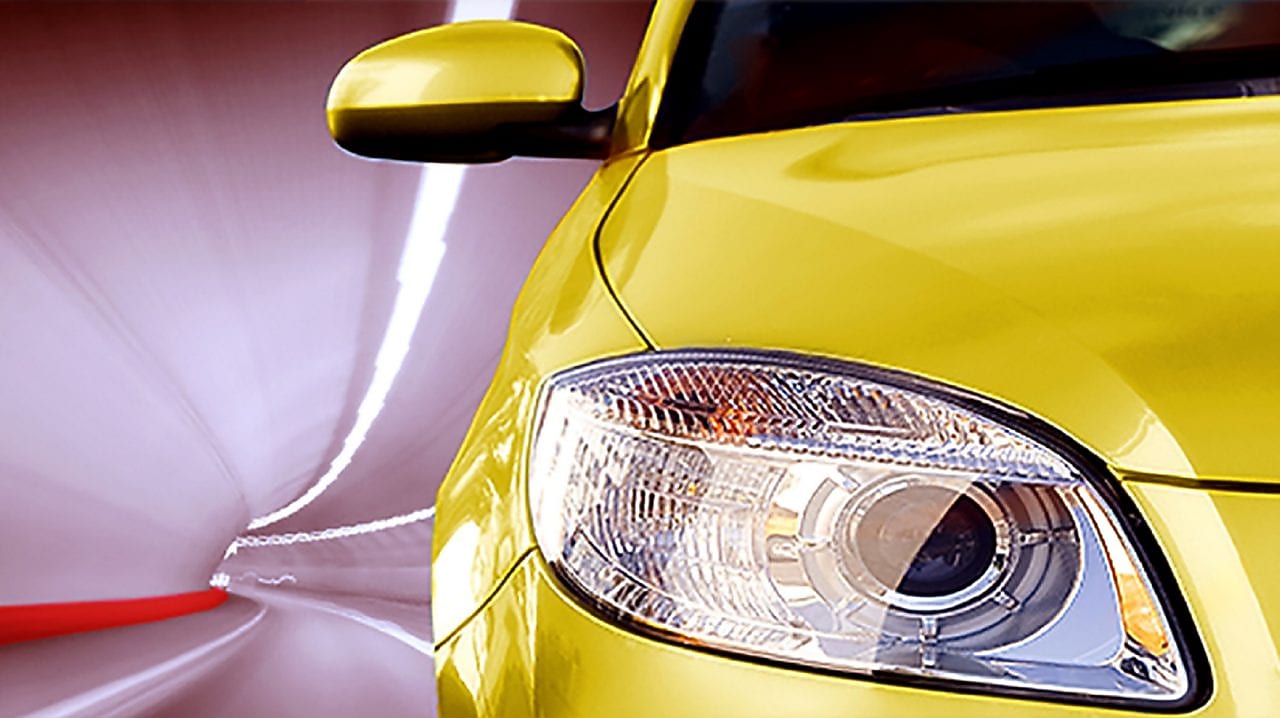 Avant d'une voiture jaune roulant dans un tunnel, phare avant droit et rétroviseur visibles