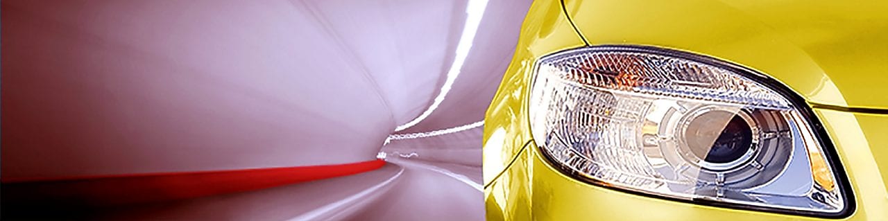 Avant d'une voiture jaune roulant dans un tunnel, phare avant droit et rétroviseur visibles