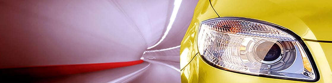 Avant d'une voiture jaune roulant dans un tunnel, phare avant droit et rétroviseur visibles