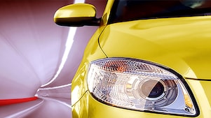 Avant d'une voiture jaune roulant dans un tunnel, phare avant droit et rétroviseur visibles