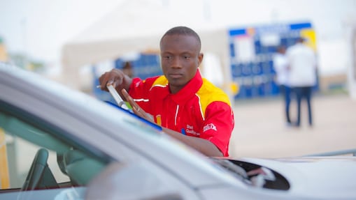 Champion de service Shell en train de s'occuper de la voiture d'un client