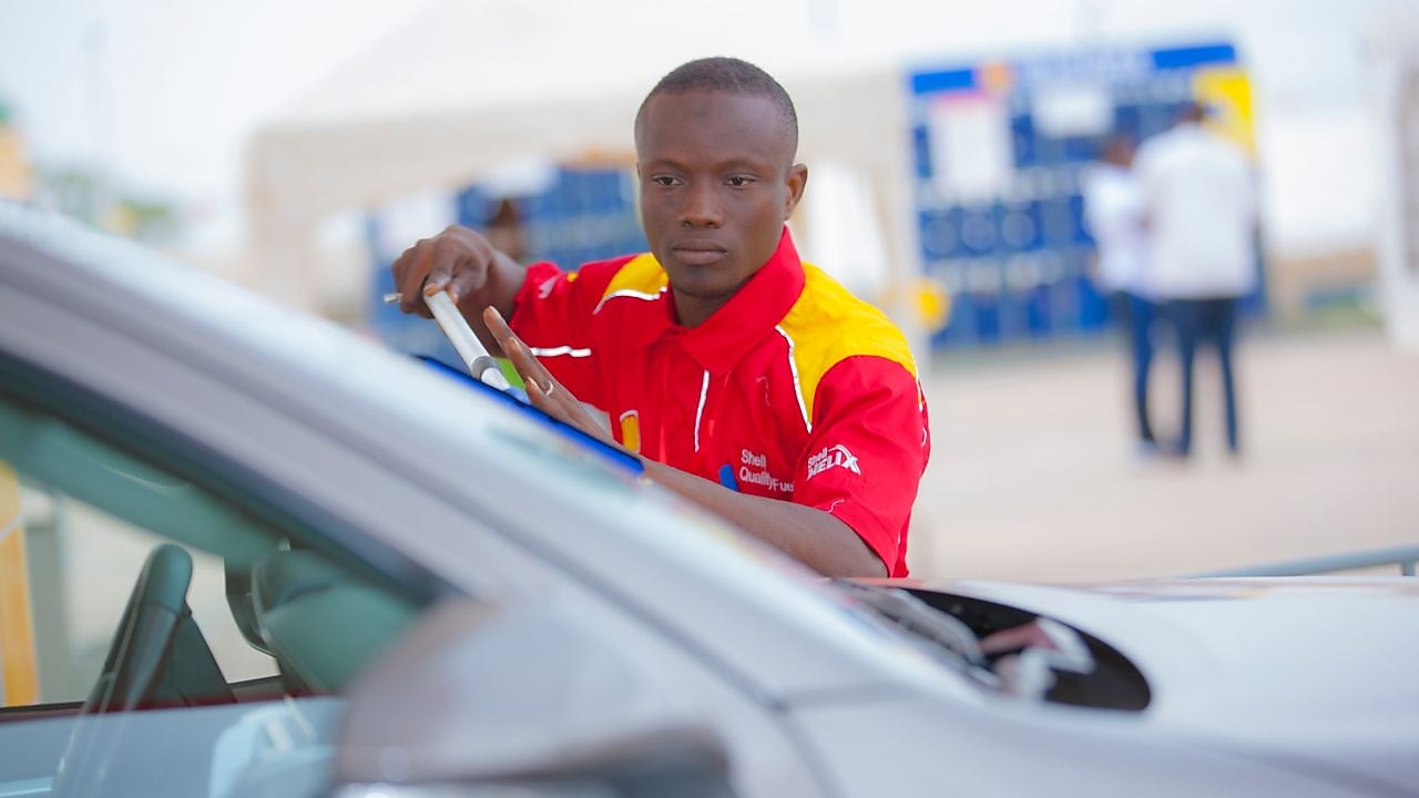 Champion de service Shell en train de s'occuper de la voiture d'un client